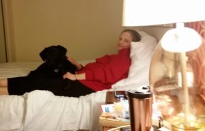 Cutest black dog ever, laying on the cutest Mother-In-Law ever in a hotel room.