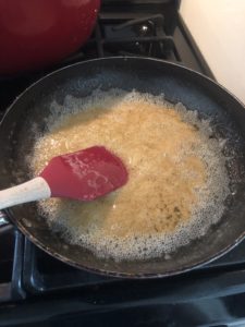 A pan with melted butter and brown sugar in it frothing lightly. 