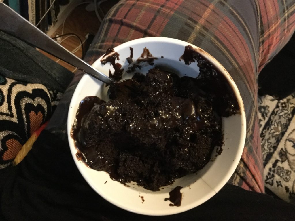 A piece of chocolate cake dumped messily in a bowl with chocolate icing all over everything.