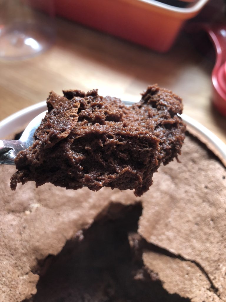 A spoonful of chocolate souffle with a very flat souffle behind it.