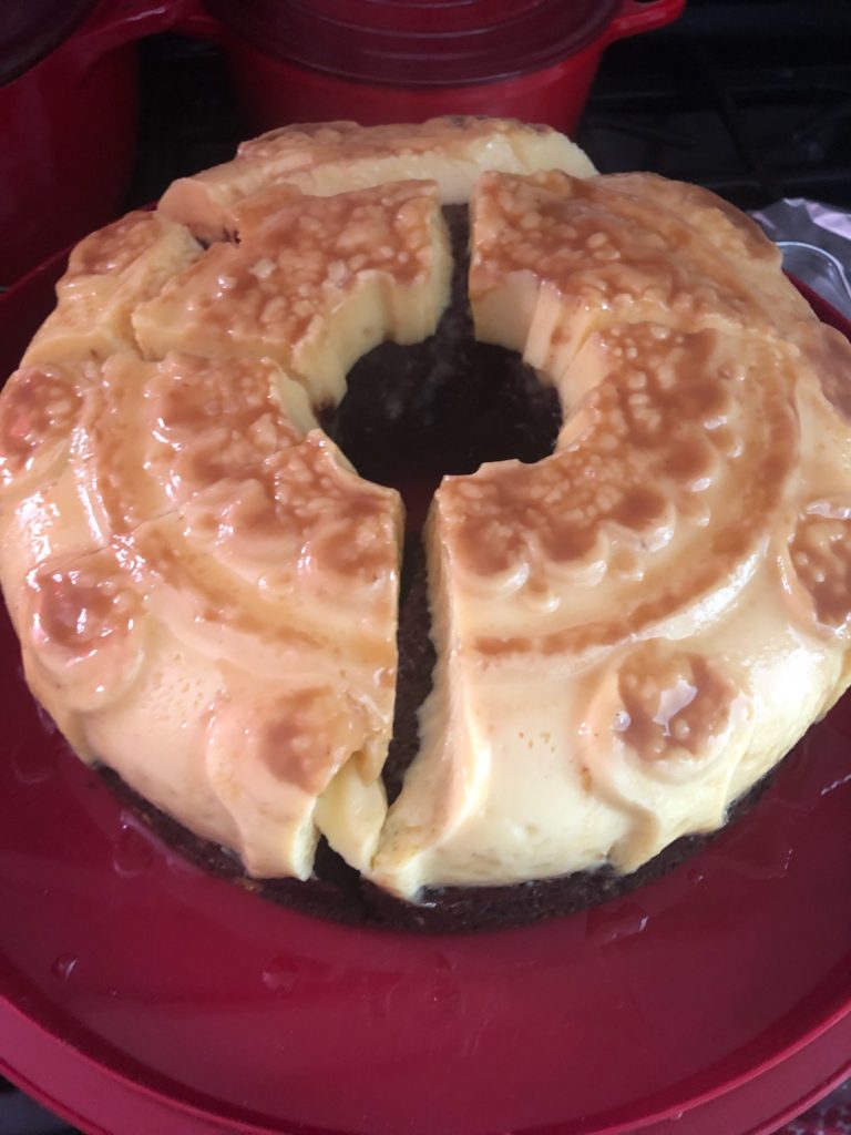 A chocolate cake with a flan type topping -- caramel has pooled in the decorations from the pan that was used.  It is split, because the cook was impatient.