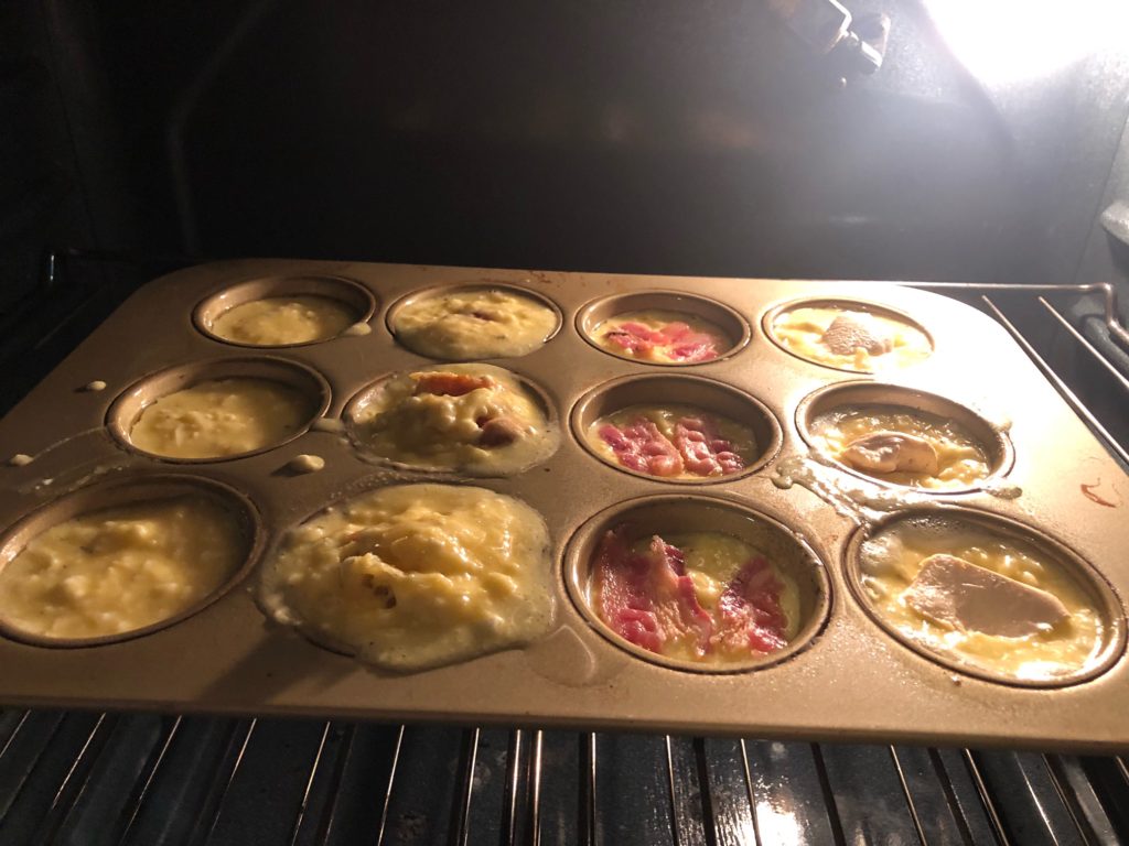 Unbaked German Baked Egg batter in a gold muffin pan in the oven. 